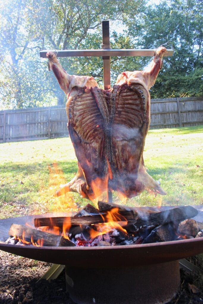 Whole lamb cooking on traditional asador cross over fire